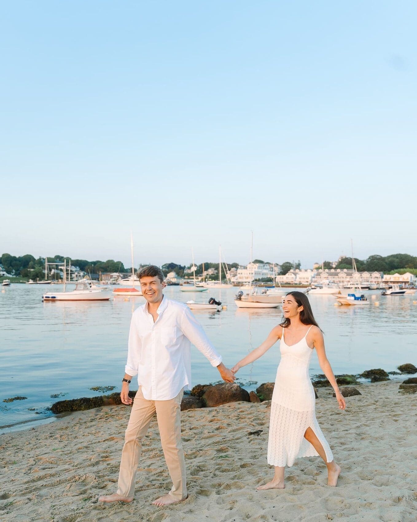 couple wearing white dress, and tan pants with white shirt, on the beach in watch hill, ri